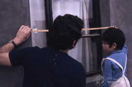 Hombre junto a un niño miden una ventana