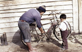 Hombre mostrando una bicicleta a un niño pequeño